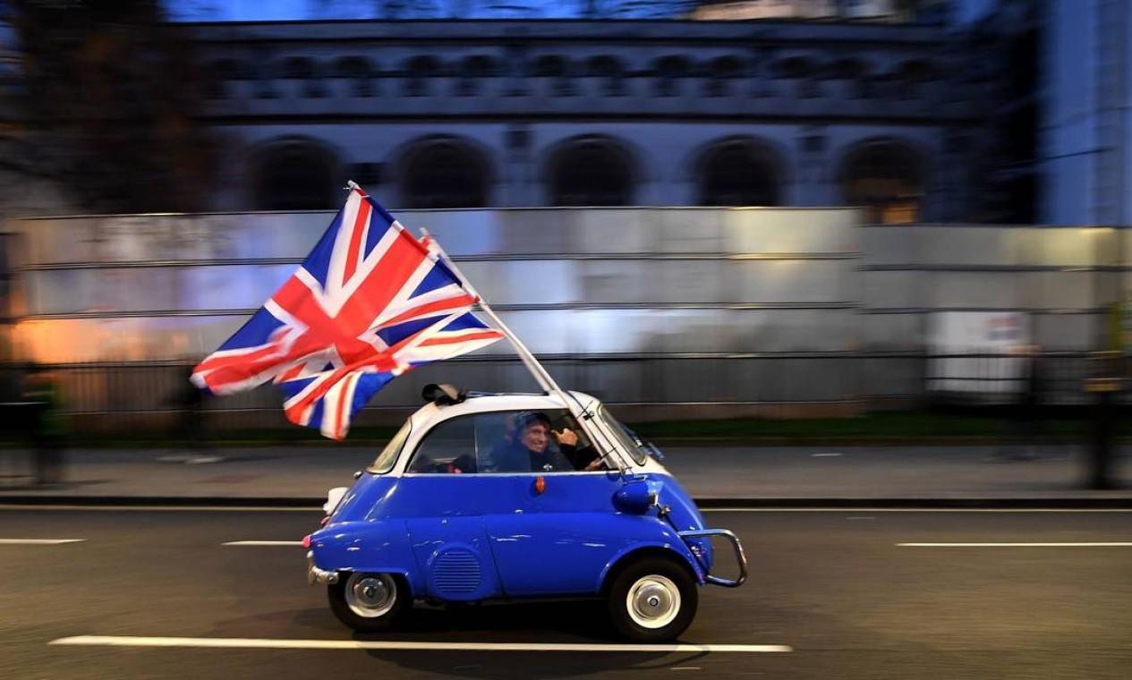 Janeiro - Homem acena bandeira do Reino Unido em um BMW Isetta ao passar por apoiadores do Brexit reunidos na Parliament Square, no centro de Londres, no dia em que o Reino Unido deixou formalmente a União Europeia – o chamado Brexit Foto: DANIEL LEAL-OLIVAS / AFP - 31/01/2020