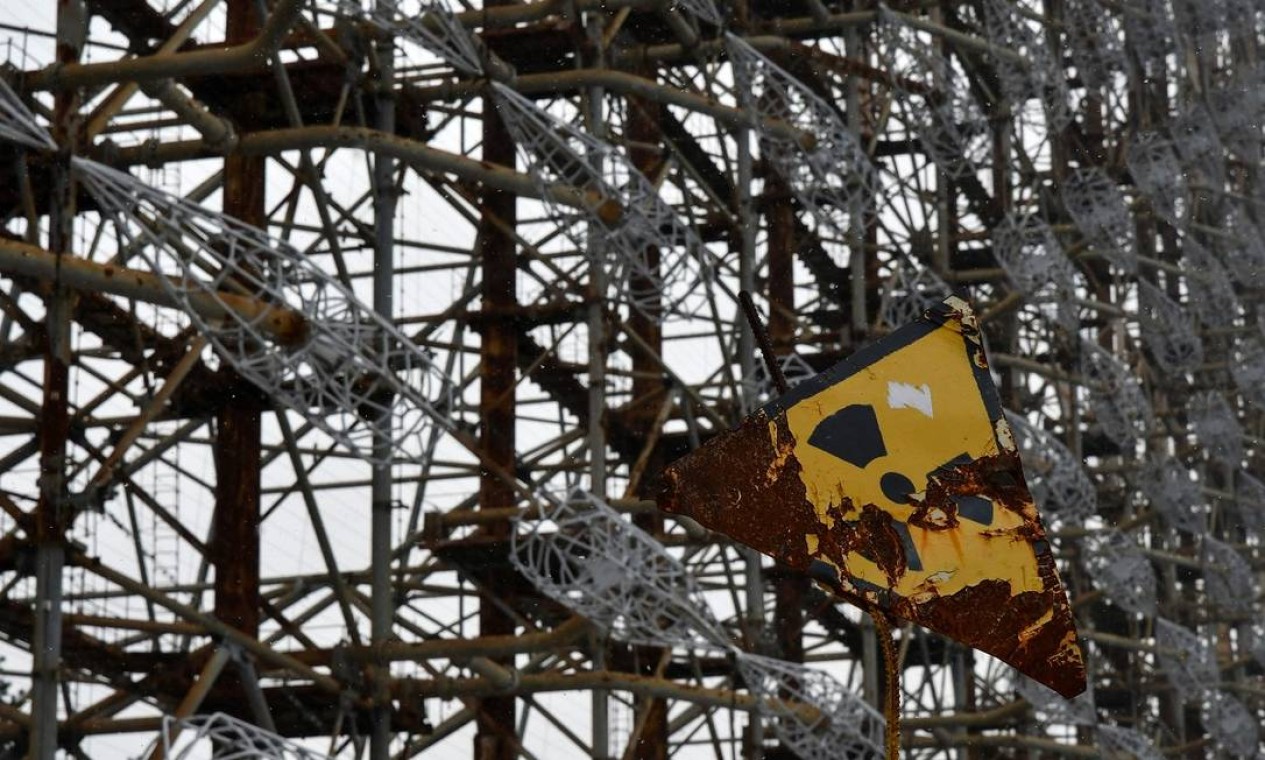Placa indicando perigo de radiação em frente ao radar Duga-1, perto da antiga usina nuclear de Chernobyl Foto: GENYA SAVILOV / AFP