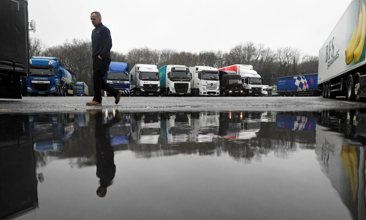 Homem caminha por pátio onde caminhões estão estacionados na área de serviço de Clacket Lane, em Westerham, Grã-Bretanha, devido à proibição de viagens do Reino Unido após descoberta de nova variante do coronavírus Foto: TOBY MELVILLE / REUTERS