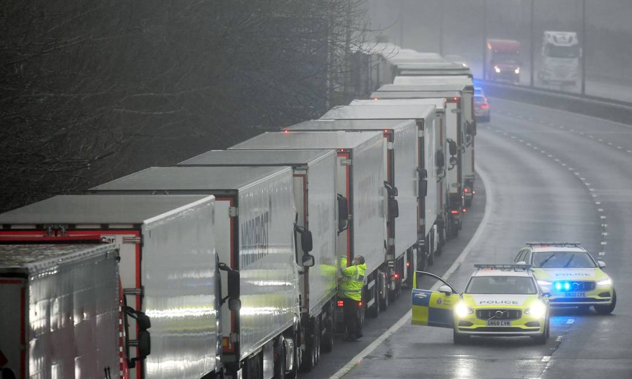 Policiais falam com um motorista de um dos caminhões estacionados na autoestrada M20 em direção ao Eurotúnel e ao Porto de Dover Foto: TOBY MELVILLE / REUTERS