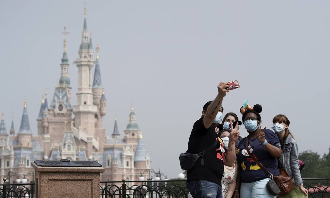 Usando máscaras, visitantes tiram uma selfie na Disneyland Shanghai, na China, o primeiro grande parque temático no mundo a reabrir ao público durante a pandemia Foto: ALY SONG / Reuters