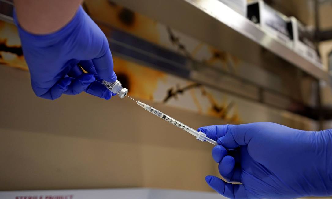 Um farmacêutico enche uma seringa com a vacina contra a Covid-19 da Pfizer-BioNTech Foto: BRYAN WOOLSTON / REUTERS