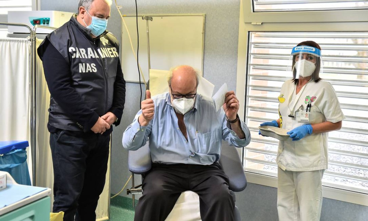 Massimo Vajani, 67 anos, comemora ao lado de um oficial Carabinieri italiano após receber a vacina Pfizer/BioNTech contra o coronavírus no hospital Civico, onde o primeiro paciente do país foi diagnosticado, em Codogno, Itália Foto: FLAVIO LO SCALZO / REUTERS