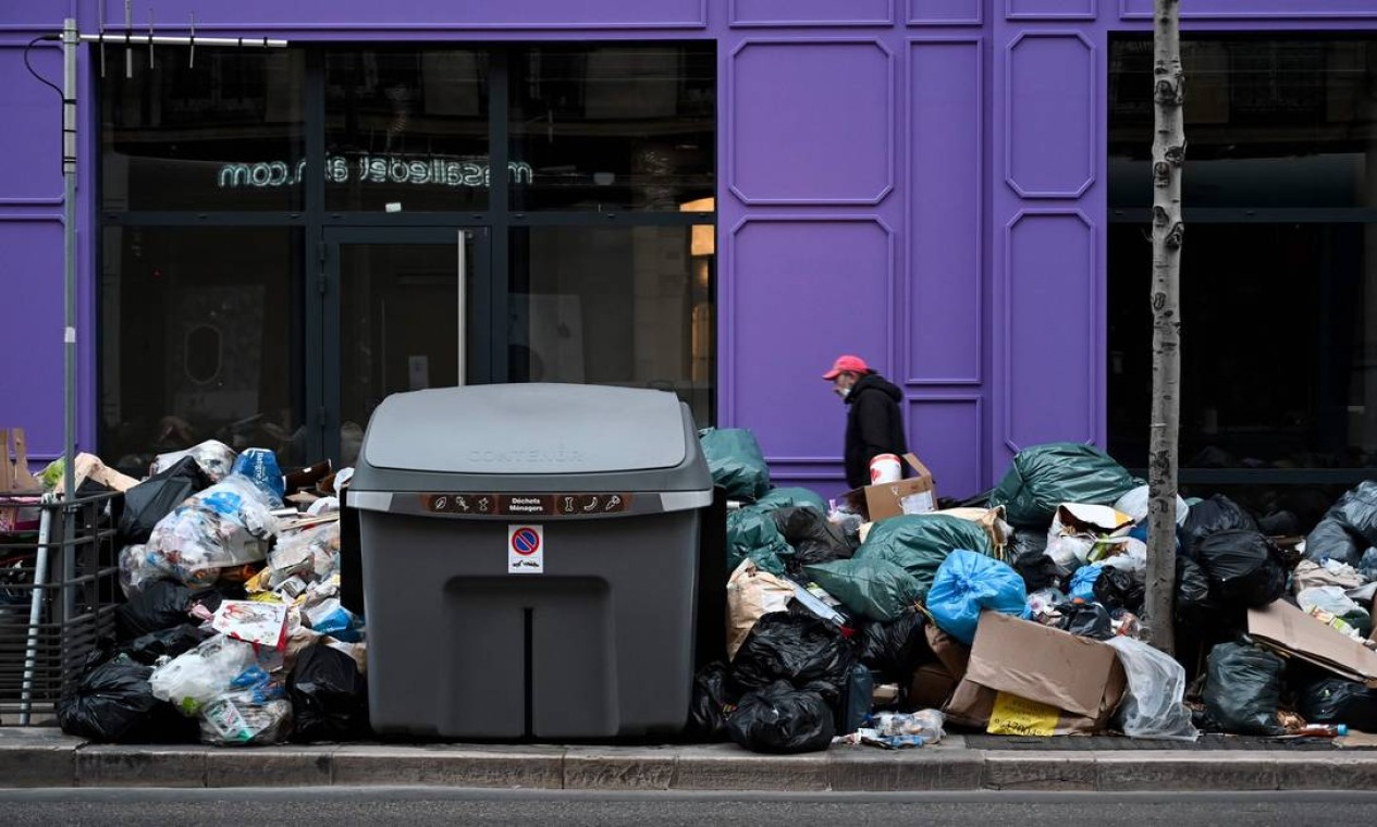 Um pedestre passa por uma pilha de lixo no segundo distrito de Marselha, sul da França, enquanto a empresa responsável pela coleta permanece em greve desde 17 de dezembro Foto: NICOLAS TUCAT / AFP