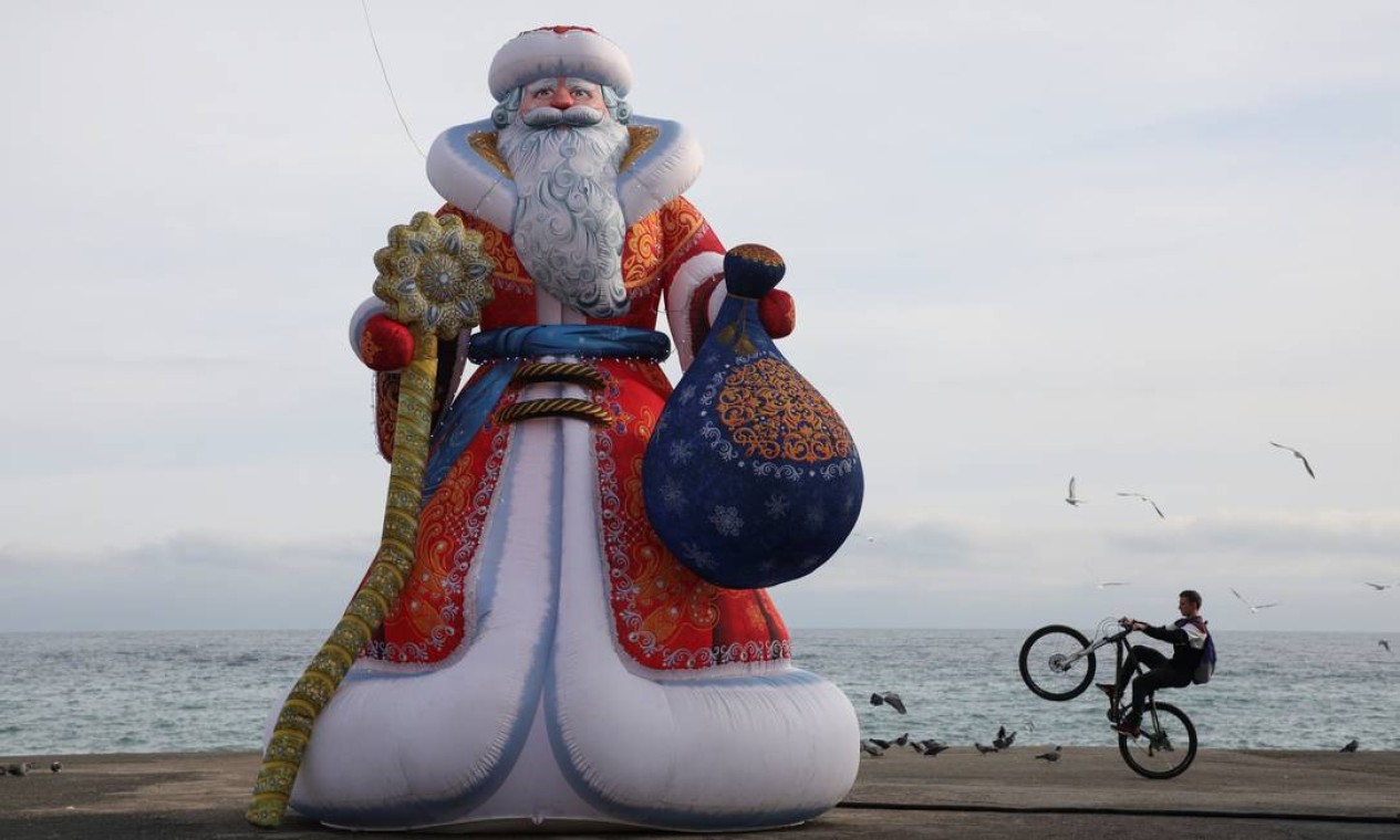 Um ciclista executa uma manobra em um aterro perto de uma figura inflável representando Ded Moroz, o equivalente russo do Papai Noel, antes da temporada de festas de Ano Novo e Natal no resort do Mar Negro de Alushta, Crimeia Foto: ALEXEY PAVLISHAK / REUTERS