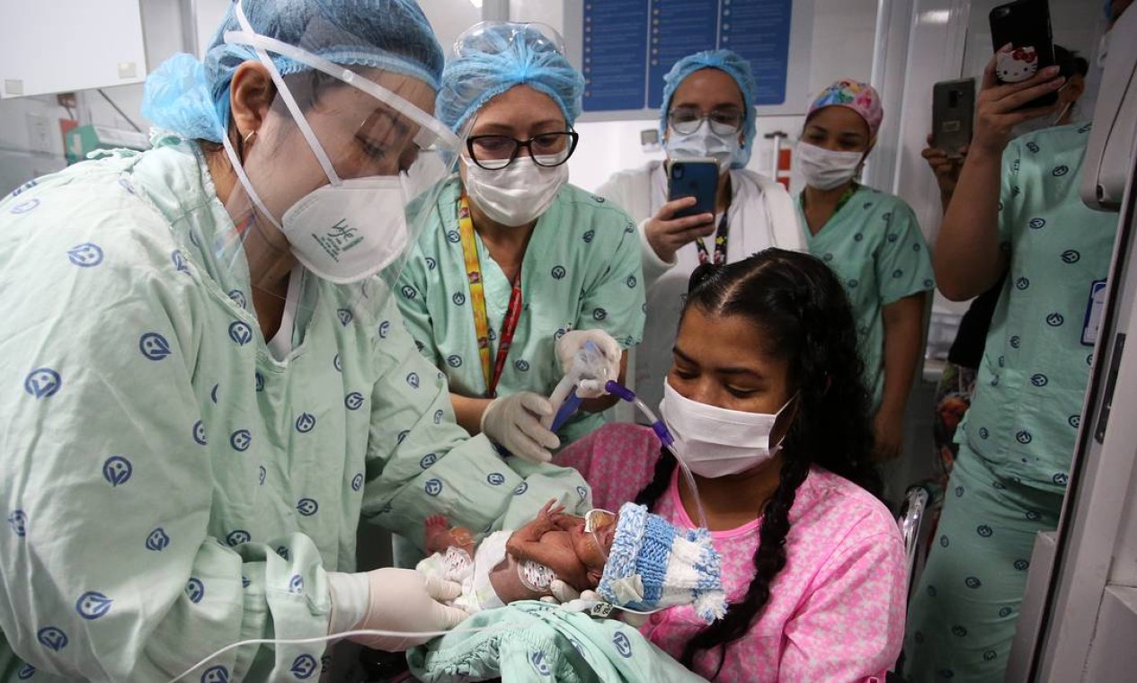 Diana Paola Angulo Mosquera, 36 anos, segura o filho recém-nascido na clínica Versalles, em Cali, na Colômbia. Ela chegou ao hospital infectada com coronavírus e com 24 semanas de gestação. Após apresentar piora no seu quadro clínico, precisou ser entubada e entrou em coma induzido para uma cesariana de urgência quando estava com 27 semanas de gravidez, e seu filho, com 875 gramas. No dia 22 de junho, ela superou a covid-19 e, após 21 dias, pôde conhecer Jefferson, que hoje respira sem ajuda de aparelhos e ganha peso a cada dia Foto: Juan Pablo Rueda / El Tiempo/Colombia/GDA
