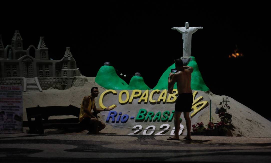 People take pictures of the Christ the Redeemer sand sculpture in Copacabana, emptied this New Year's Eve by the Covid-19 pandemic Photo: Brenno Carvalho / Agência O Globo