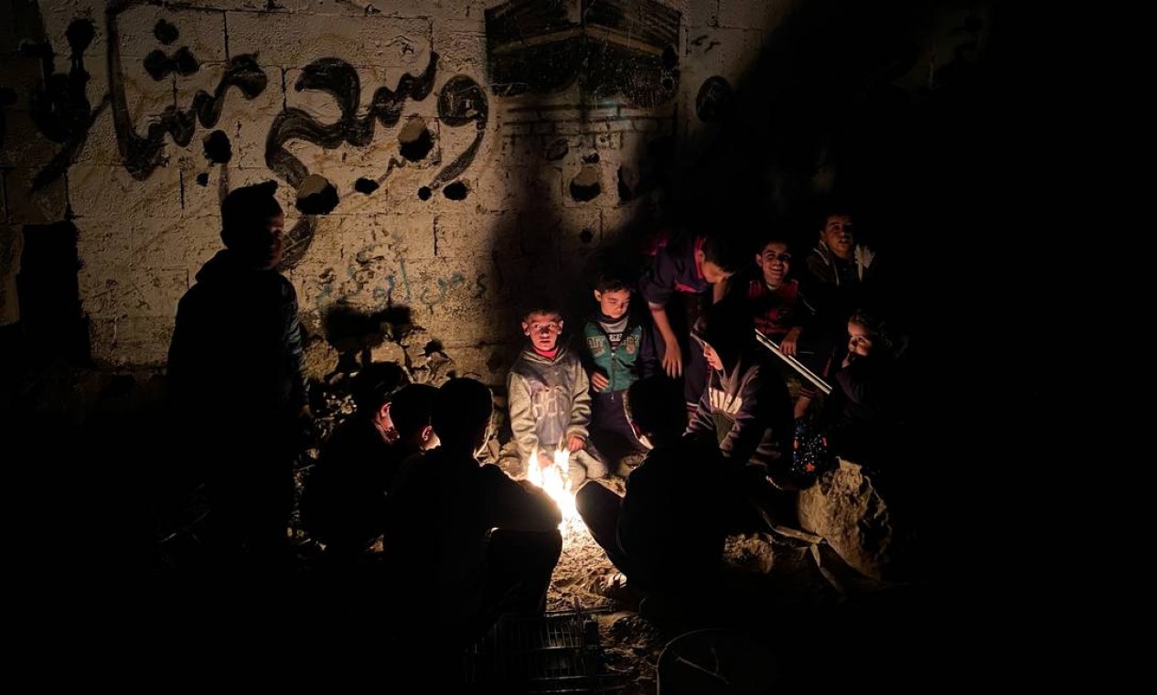 Palestinos se aquecem em volta de uma fogueira em um dia de inverno, durante o bloqueio para prevenir a propagação da COVID-19, no norte da Faixa de Gaza Foto: MOHAMMED SALEM / REUTERS