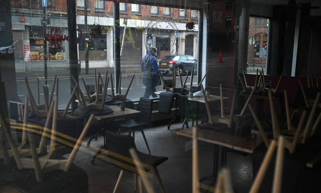 Homem passa por um café fechado em Manchester. Bares e restaurantes já estavam fechados, e as determinações para reuniões sociais também já eram bem restritas Foto: OLI SCARFF / AFP