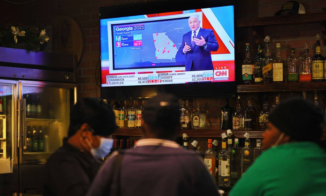 Pessoas aproveitam happy hour em bar de Atlanta, na Geórgia, enquanto as notícias da eleição são mostradas na televisão Foto: Michael M. Santiago / AFP/05-01-2021