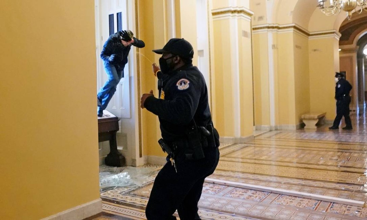 Um policial do Capitólio atira spray de pimenta em um manifestante que tenta entrar no prédio do Congresso Foto: POOL / REUTERS