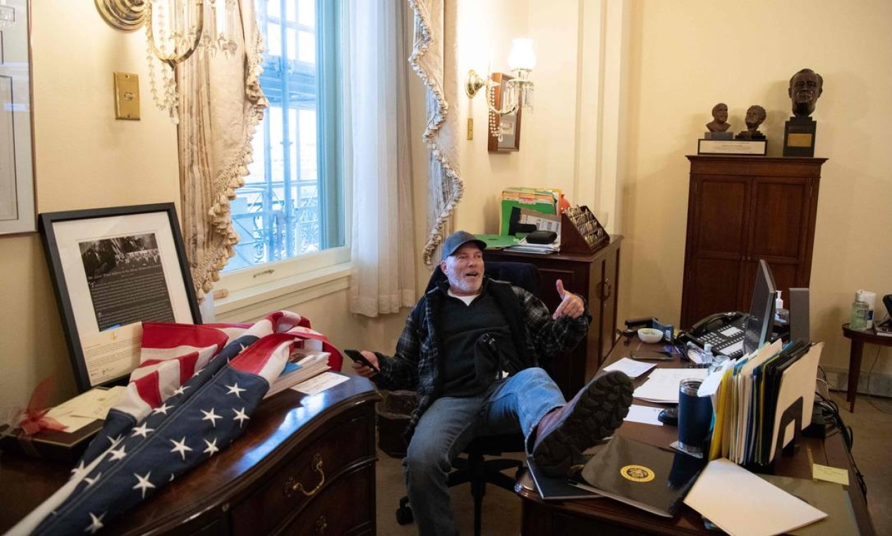 Um manifestante senta-se no gabinete da presidente da Câmara, Nancy Pelosi, durante invasão ao prédio do Capitólio Foto: SAUL LOEB / AFP