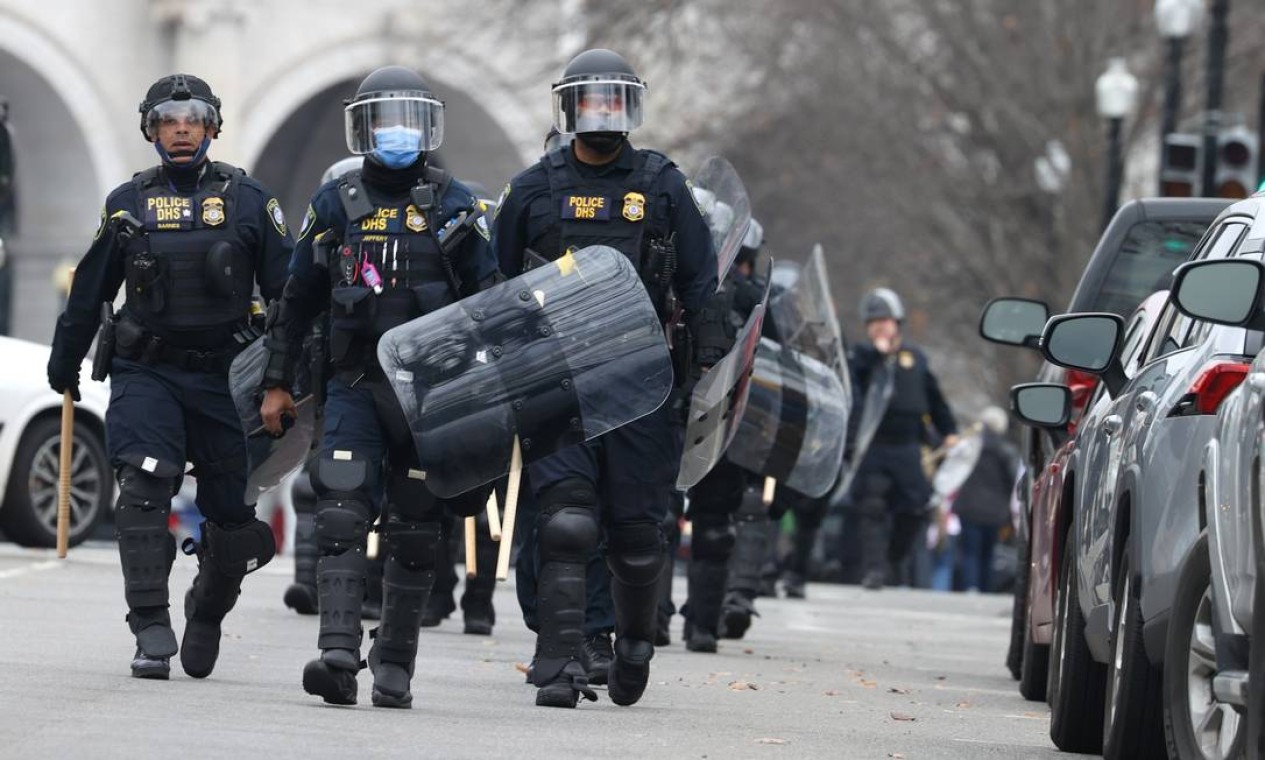 Policiais em traje antimotim caminham em direção ao Capitólio dos EUA enquanto os manifestantes invadem o prédio Foto: TASOS KATOPODIS / AFP