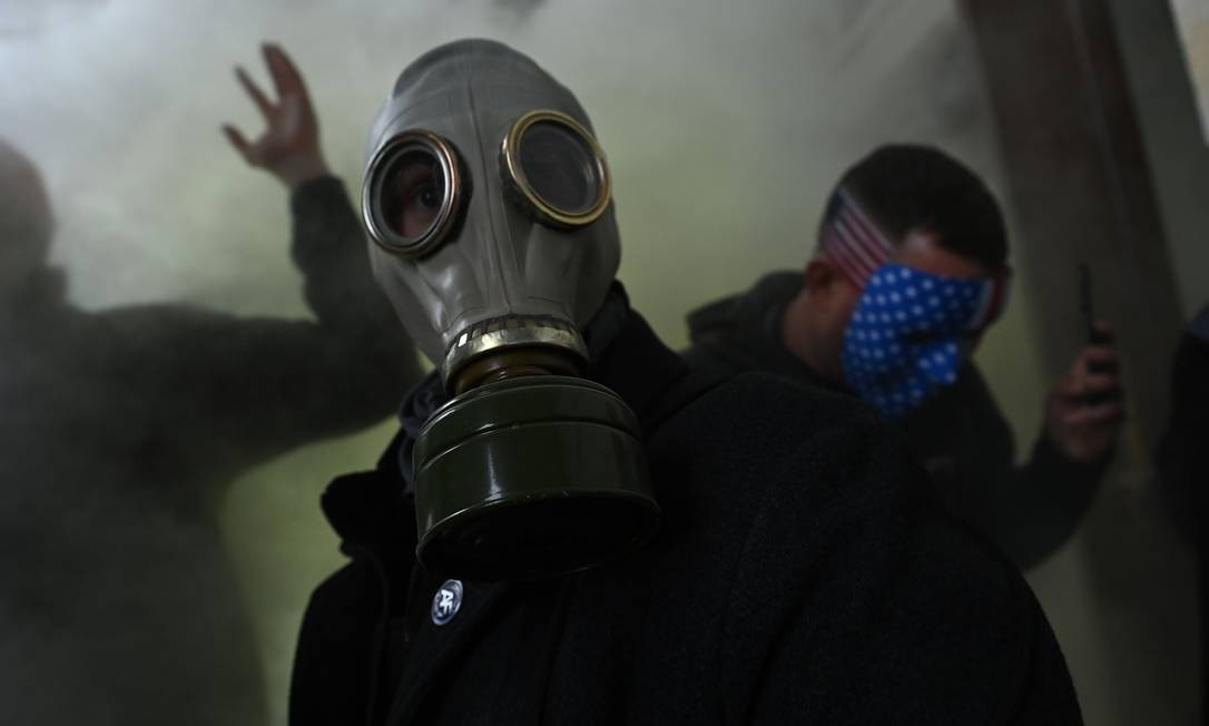 Apoiador de Trump usa uma máscara de gás enquanto invade o Congresso americano Foto: BRENDAN SMIALOWSKI / AFP