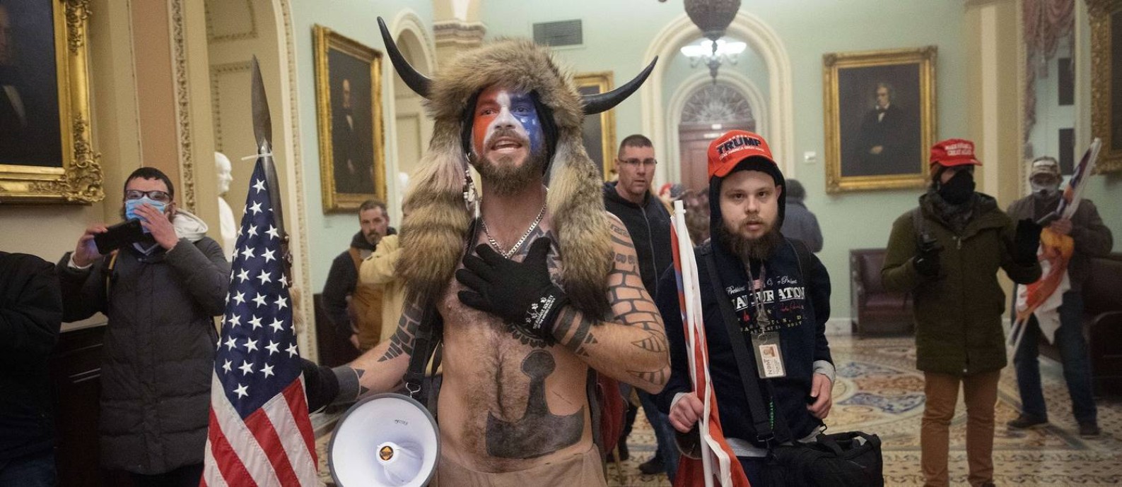 Usando pele animal, chapéu com chifres e rosto pintado, apoiador da QAnon rouba a cena na invasão ao Congresso americano Foto: WIN MCNAMEE / AFP/06-01-2021