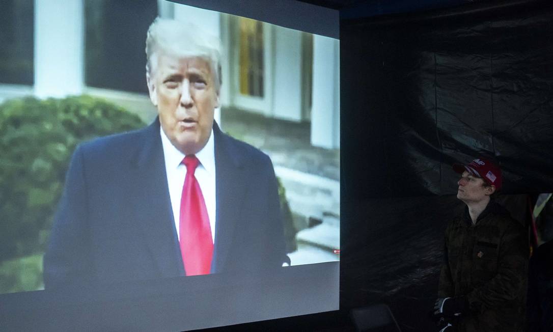 Apoiador de Donald Trump no estado do Oregon assiste a mensagem do presidente depois de invasão do Capitólio. Vídeo acabou removido das principais plataformas Foto: Nathan Howard / AFP