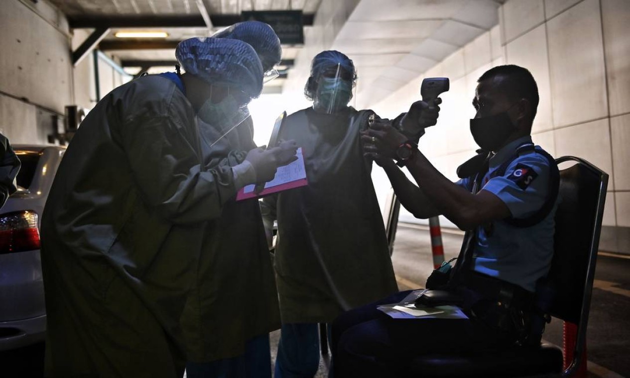 Equipe médica registra um segurança para teste de coronavírus em um hospital privado em Bangkok, depois que o governo tailandês impôs novas restrições devido ao recente surto de Covid-19 Foto: LILLIAN SUWANRUMPHA / AFP