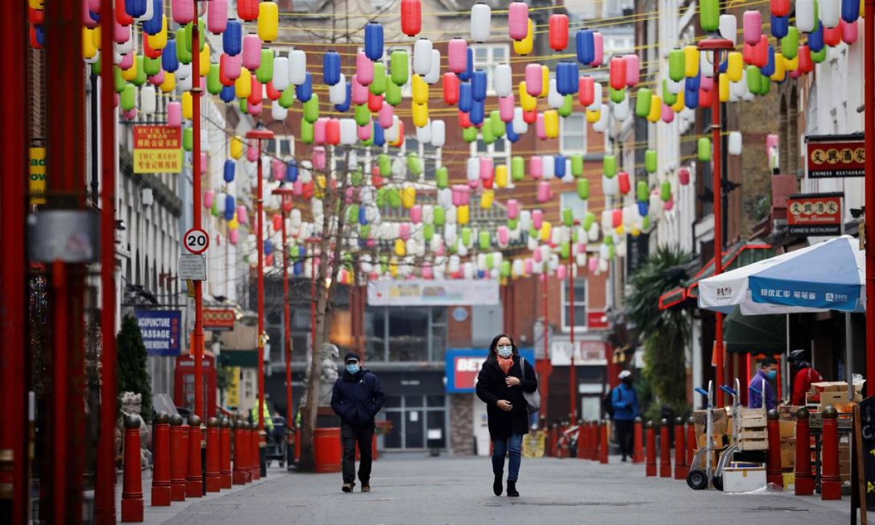 Pedestres usam máscaras durante a caminhada em Chinatown, no centro de Londres, quando a Inglaterra entra em um terceiro bloqueio devido ao novo coronavírus Foto: TOLGA AKMEN / AFP