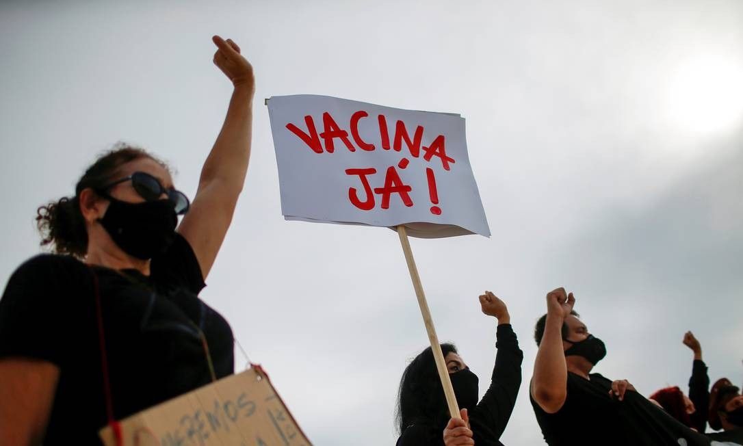 "Vacina já", diz um cartaz erguido por manifestante durante ato em Brasília nesta sexta-feira, após o Brasil atingir a marca de 200 mil mortes pela Covid-19 Foto: ADRIANO MACHADO / REUTERS