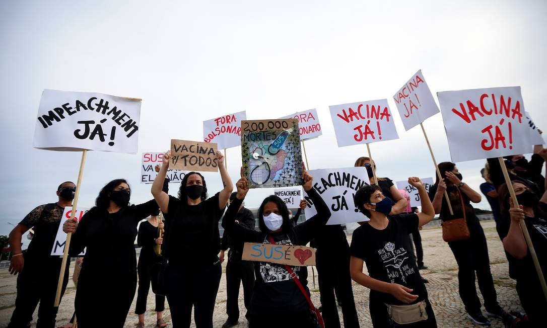 Vestidos de preto em sinal de luto, manifestantes exibem cartazes em que pedem o impeachment do presidente e vacina contra a Covid-19 Foto: ADRIANO MACHADO / REUTERS