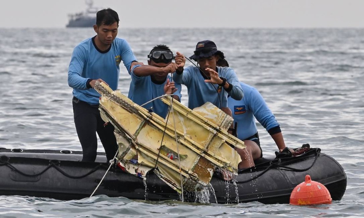Mergulhadores da Marinha da Indonésia seguram destroços do voo SJY182 da Sriwijaya Air durante uma operação de busca e resgate no mar perto da ilha de Lancang Foto: ADEK BERRY / AFP