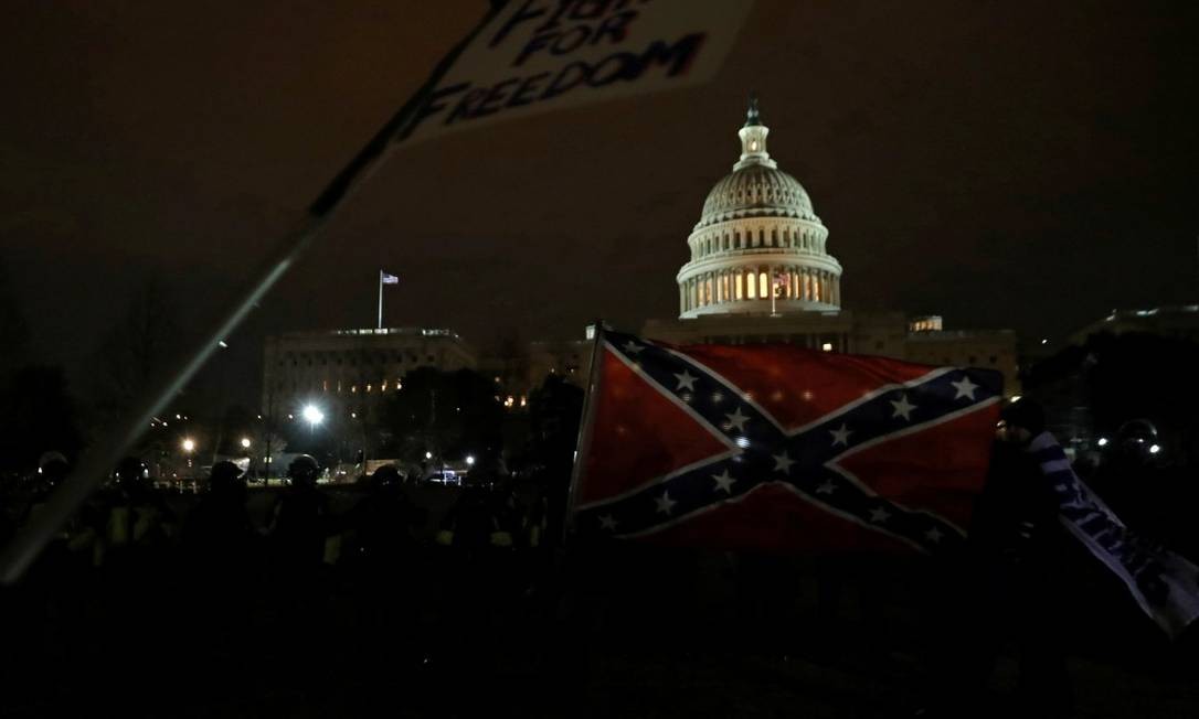 Manifestante pró-Trump carregam bandeira dos estados confederados, com o Capitólio ao fundo Foto: LEAH MILLIS / REUTERS / 6-1-21
