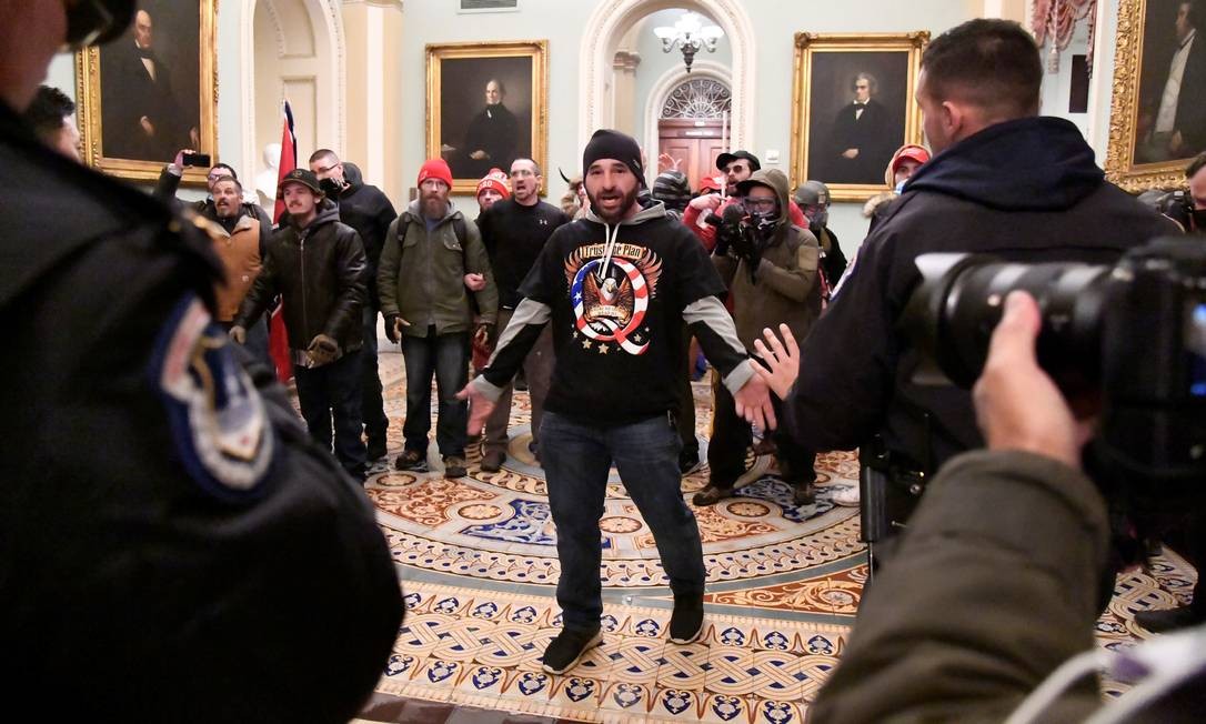 DOUG JENSEN, 41 anos, morador do estado de Iowa, foi preso pelo FBI na madrugada de sábado. Doug foi reconhecido em imagem que se tornou icônica durante o motim no Capitólio. É ele o homem que, vestindo um boné de tricô e uma camiseta da QAnon com uma águia, aparece com os braços abertos enfrentando seguranças do Congresso Foto: MIKE THEILER / REUTERS