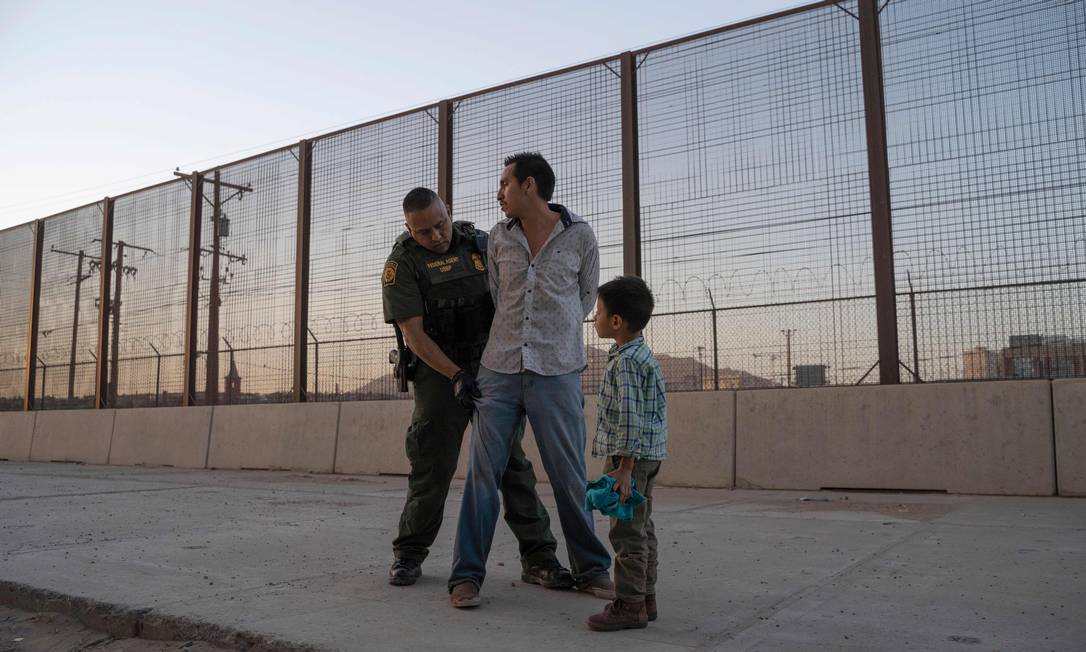 José, 27 anos, com seu filho José Daniel, 6, é revistado pelo agente da Alfândega e Proteção de Fronteiras dos EUA, Frank Pino, em maio de 2019, em El Paso, Texas. Pai e filho passaram um mês viajando pela Guatemala através do México. À época, cerca de 1.100 migrantes da América Central e de outros países tentavam cruzar para o setor de fronteira de El Paso a cada dia, refletindo uma das maiores crise de imigração da história Foto: PAUL RATJE / AFP - 16/05/2019