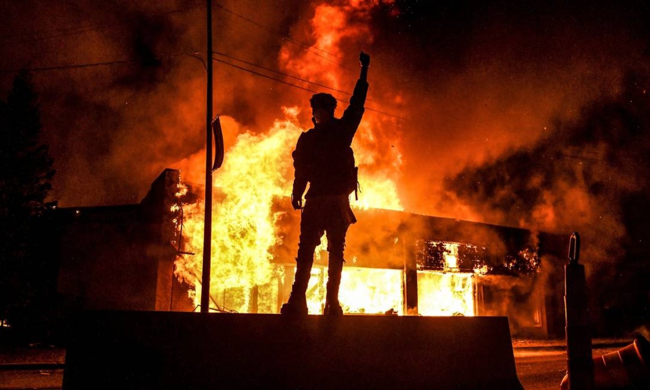 Um manifestante reage em frente a um prédio em chamas durante uma manifestação em Minneapolis, Minnesota, em 29 de maio. Protestos antirracistas eclodiram pelos EUA após a morte de George Floyd. Movimento negro e contra a violência policial pautou a disputa eleitoral Foto: CHANDAN KHANNA / AFP - 29/05/2020