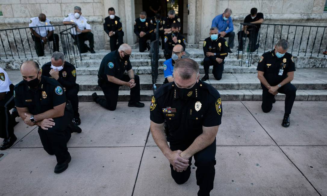 Policiais se ajoelham durante um protesto em Coral Gables, Flórida, em 30 de maio, em resposta à morte de George Floyd. Confrontos estouraram nas principais cidades, com manifestantes furiosos que ignoravam as advertências de Trump de que seu governo impediria protestos violentos sobre a brutalidade policial Foto: EVA MARIE UZCATEGUI / AFP - 30/05/2020