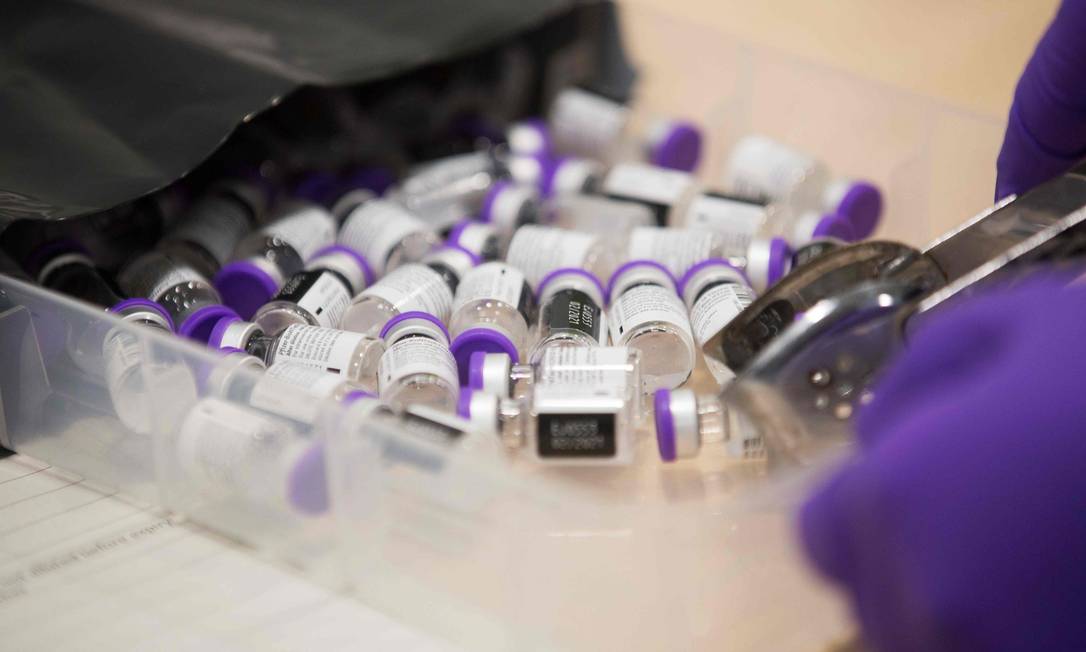 Um membro da equipe médica pega um frasco da vacina da Pfizer-BioNTech contra Covid-19 Foto: GRAEME ROBERTSON / AFP