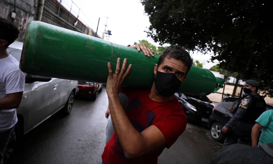 Um homem carrega um cilindro de oxigênio enquanto parentes de pacientes hospitalizados ou em atendimento domiciliar tentam comprar o insumo, indispensável no tratamento de pacientes com quadro grave da Covid-19 Foto: BRUNO KELLY / REUTERS