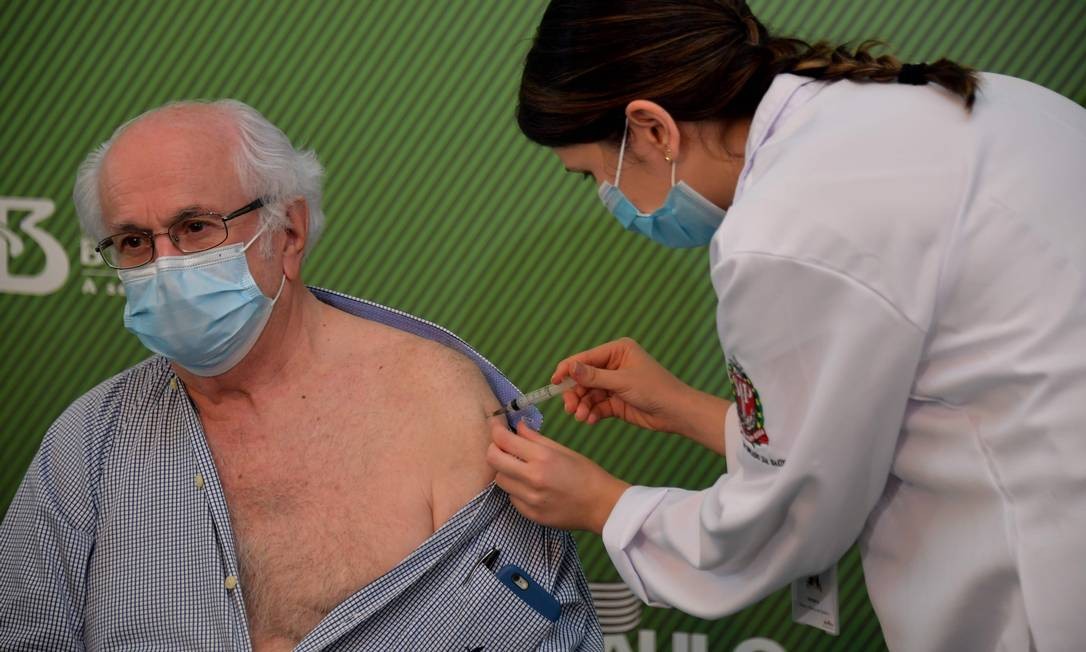 O médico Almir Ferreira de Andrade, 79 anos, recebe dose da vacina CoronaVac contra o coronavírus. O governador de São Paulo, João Doria (PSDB), afirmou neste domingo que determinou ao Butantan a entrega das doses de CoronaVac ao Ministério da Saúde para que sejam distribuídas a outros estados brasileiros Foto: NELSON ALMEIDA / AFP