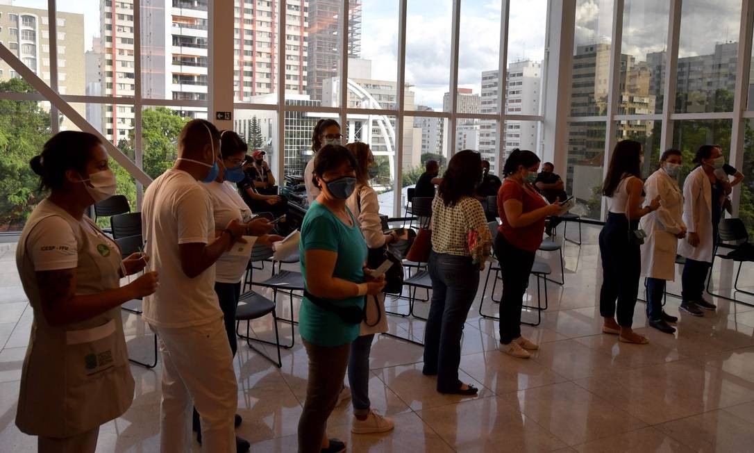 Profissionais de saúde fazem fila para receber a primeira dose da vacina CoronaVac no Hospital das Clínicas, em São Paulo Foto: NELSON ALMEIDA / AFP