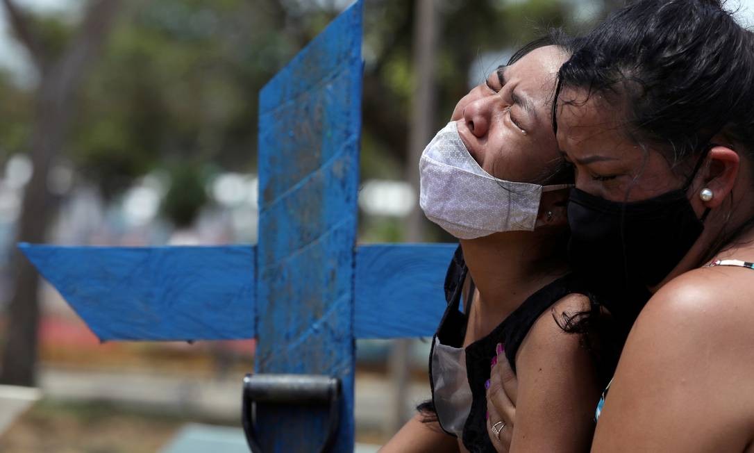 Jovem é amparada pela tia ao durante o sepultamento de sua mãe, Andrea dos Reis Brasão, 39 anos, que faleceu em decorrência da Covid-19, no cemitério Parque Tarumã, em Manaus Foto: BRUNO KELLY / REUTERS