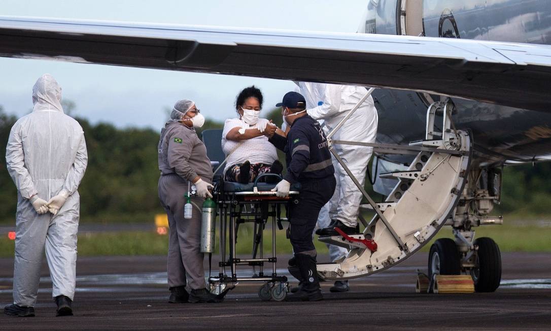 Paciente com Covid-19 é recebe atendimento de equipe médica no aeroporto de Ponta Pelada, em Manaus, antes de ser transferida para outro estado em avião militar Foto: MICHAEL DANTAS / AFP