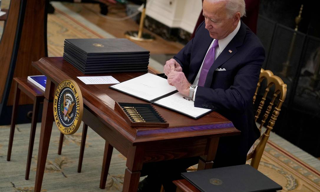 Joe Biden assina uma das 10 ordens executivas relacionadas ao combate ao novo coronavírus nos EUA Foto: MANDEL NGAN / AFP
