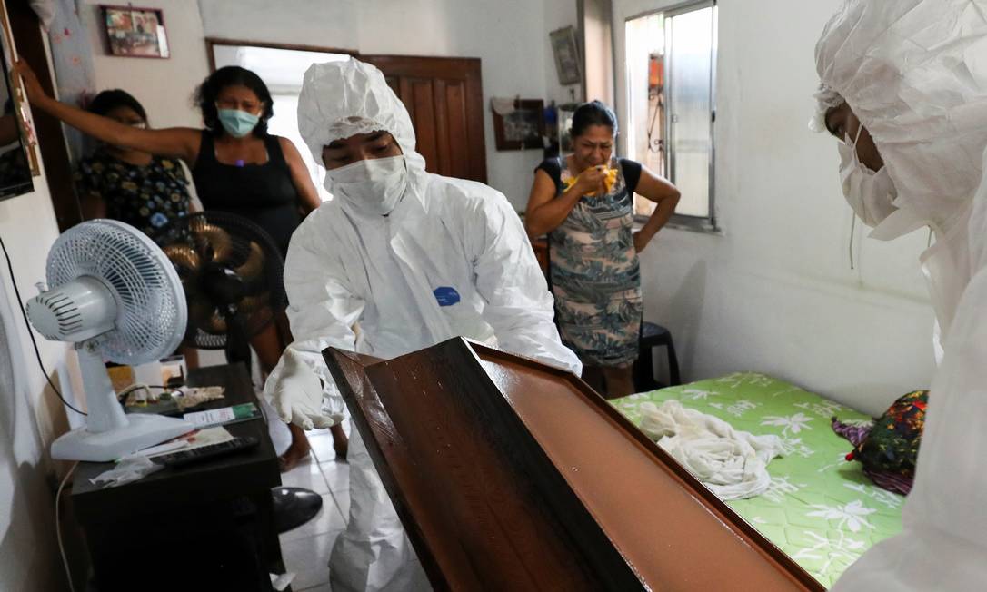 Funcionários de funerária retiram corpo de vítima da Covid-19, que morreu em sua casa em Manaus. Foto: BRUNO KELLY / REUTERS