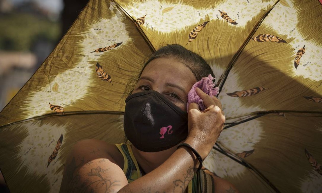 Selma de Freitas, 54 anos, trabalha de ambulante na Central do Brasil. Ela conta que usa sombrinha e uma toalha para limpar o suor e que evita tirar a máscara do rosto Foto: Márcia Foletto / Agência O Globo