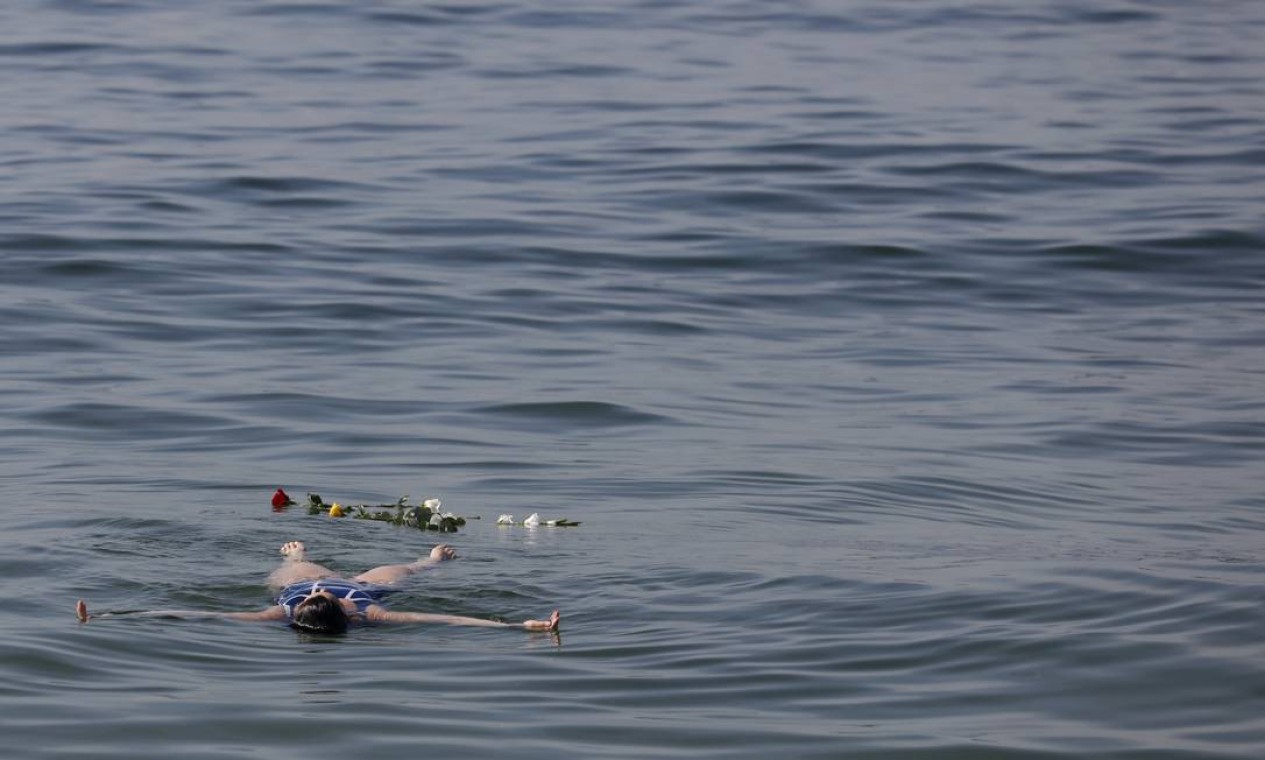 No Arpoador, um mulher nada perto de flores jogadas no mar em homenagem à Iemanjá Foto: Luiza Moraes / Agência O Globo