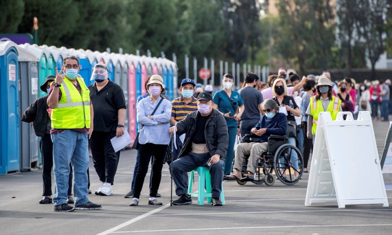 Pessoas esperam na fila em um estacionamento da Disneylândia para receber as vacinas contra a Covid-19 no parque temático, em Anaheim, Califórnia Foto: VALERIE MACON / AFP - 14/01/2021