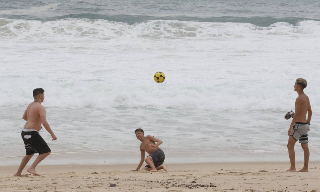 Amigos jogam altinha à beira-mar, diante da ressaca que afugentou banhistas Foto: Cléber Júnior / Agência O Globo