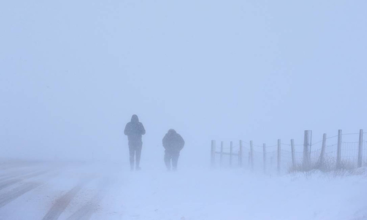Duas pessoas caminham sobre a neve durante uma nevasca em Saddleworth, norte da Inglaterra Foto: LINDSEY PARNABY / AFP - 8/02/2021