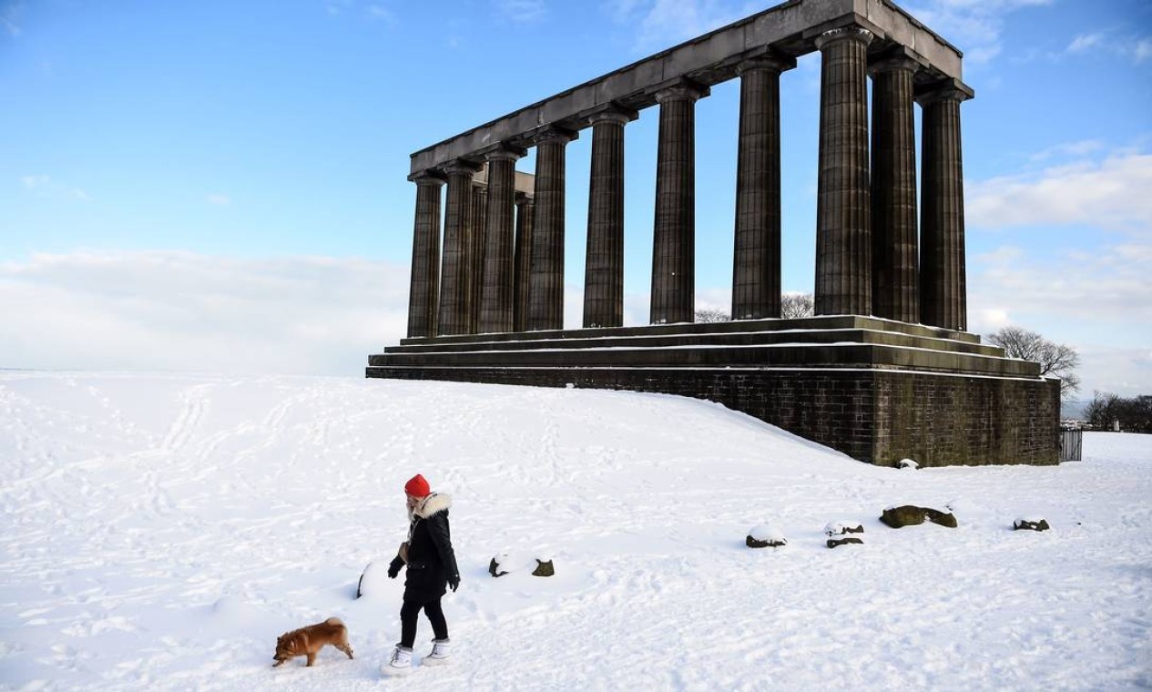 Mulher caminha com um cachorro pelo Monumento Nacional no Calton Hill coberto de neve, no centro de Edimburgo Foto: ANDY BUCHANAN / AFP