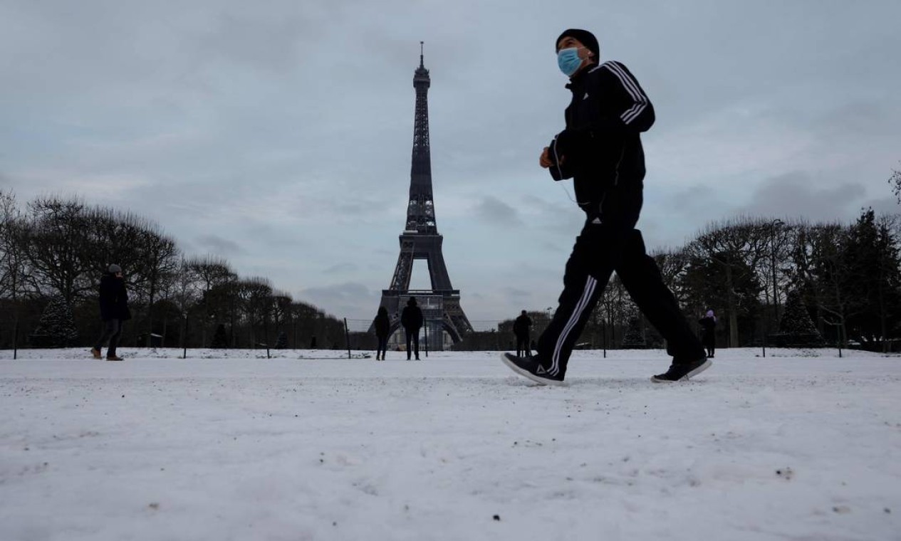 Homem passa pela Torre Eiffel após uma leve nevasca durante a noite, em Paris Foto: LUDOVIC MARIN / AFP 10/02/2021
