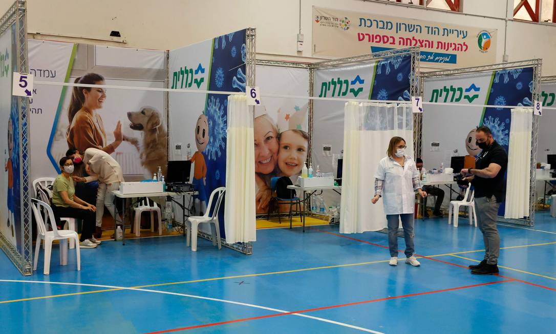  Israelenses são vacinados em Hod HaSharon, no centro do país, que também lidera o ranking da proporção da população que já recebeu as duas doses, 27%. Ainda assim, traumas da pandemia deixam os cidadãos desconfiados Foto: JACK GUEZ / AFP
