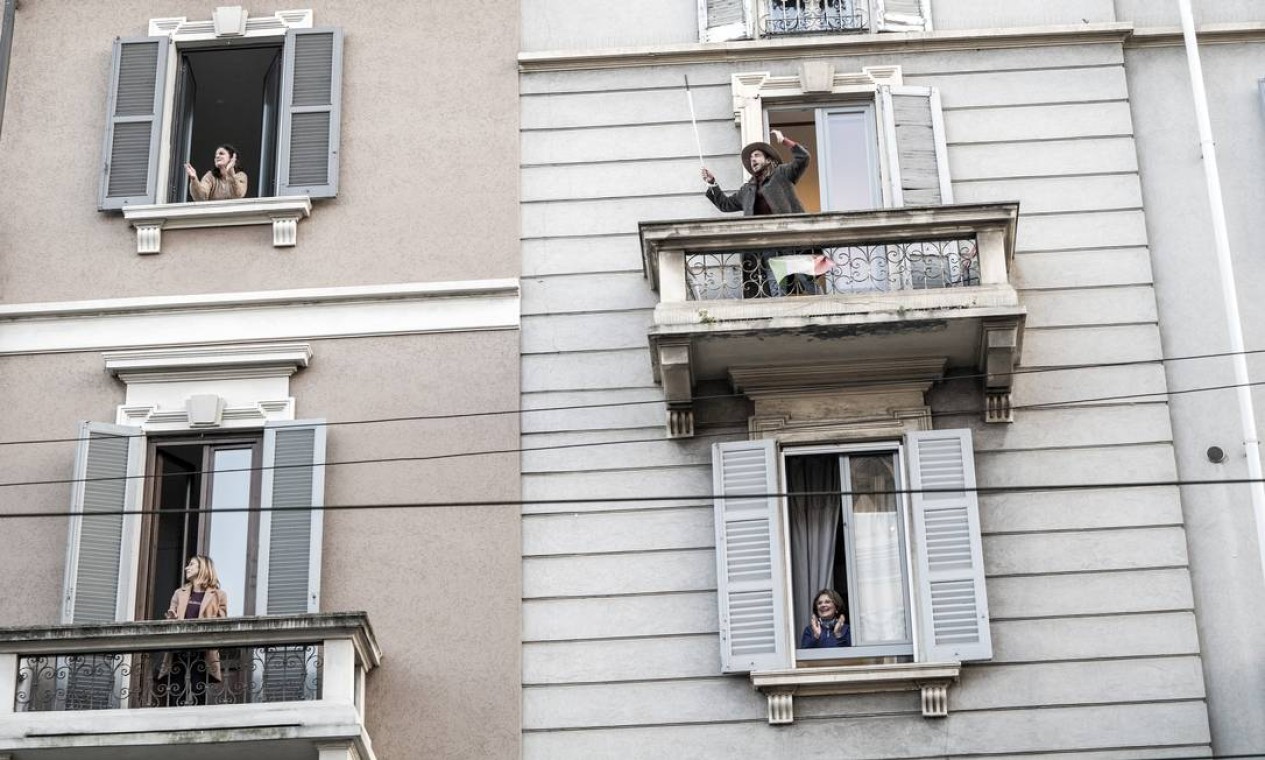 Vizinhos interagem das sacadas de seus apartamentos em Milão, Itália, em março de 2020. Novas formas de
socializar em tempos de pandemia Foto: ALESSANDRO GRASSANI / The New York Times
