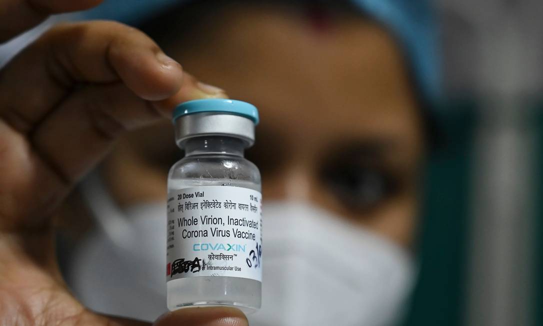 Profissional de saúde segura frasco da vacina indiana Covaxin, na Índia Foto: DIBYANGSHU SARKAR / AFP