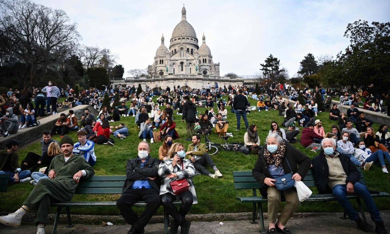 Pessoas se reúnem e se sentam em frente à Basílica do Sagrado Coração, no topo da colina de Montmartre, em Paris, França Foto: ANNE-CHRISTINE POUJOULAT / AFP