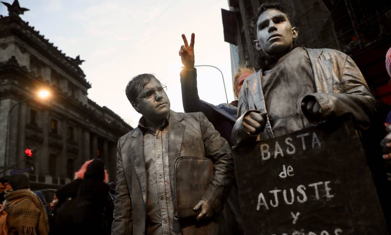 Manifestantes pintados de cinza seguram uma placa que diz "Chega de demissões nem ajustes" durante um protesto em Buenos Aires, em 2018 Foto: Marcos Brindicci / Reuters